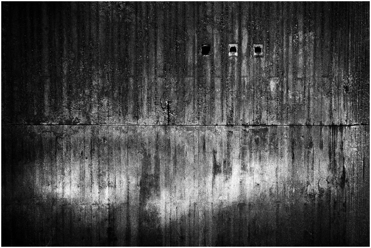 Schwarz-weiß-Fotografie: Betonmauer mit drei Löchern (NANB) an der Ruhr-Universität Bochum