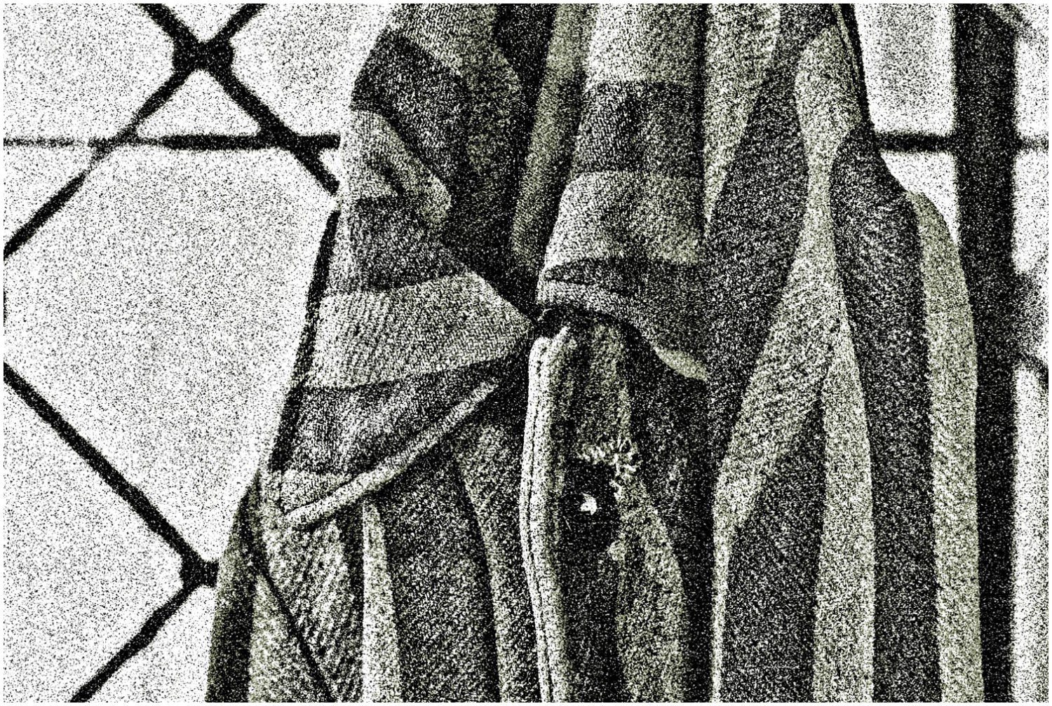 Ausschnitt einer gestreiften Gefängnisjacke, die an einem Haken hängt, grobkörnig verfremdet.