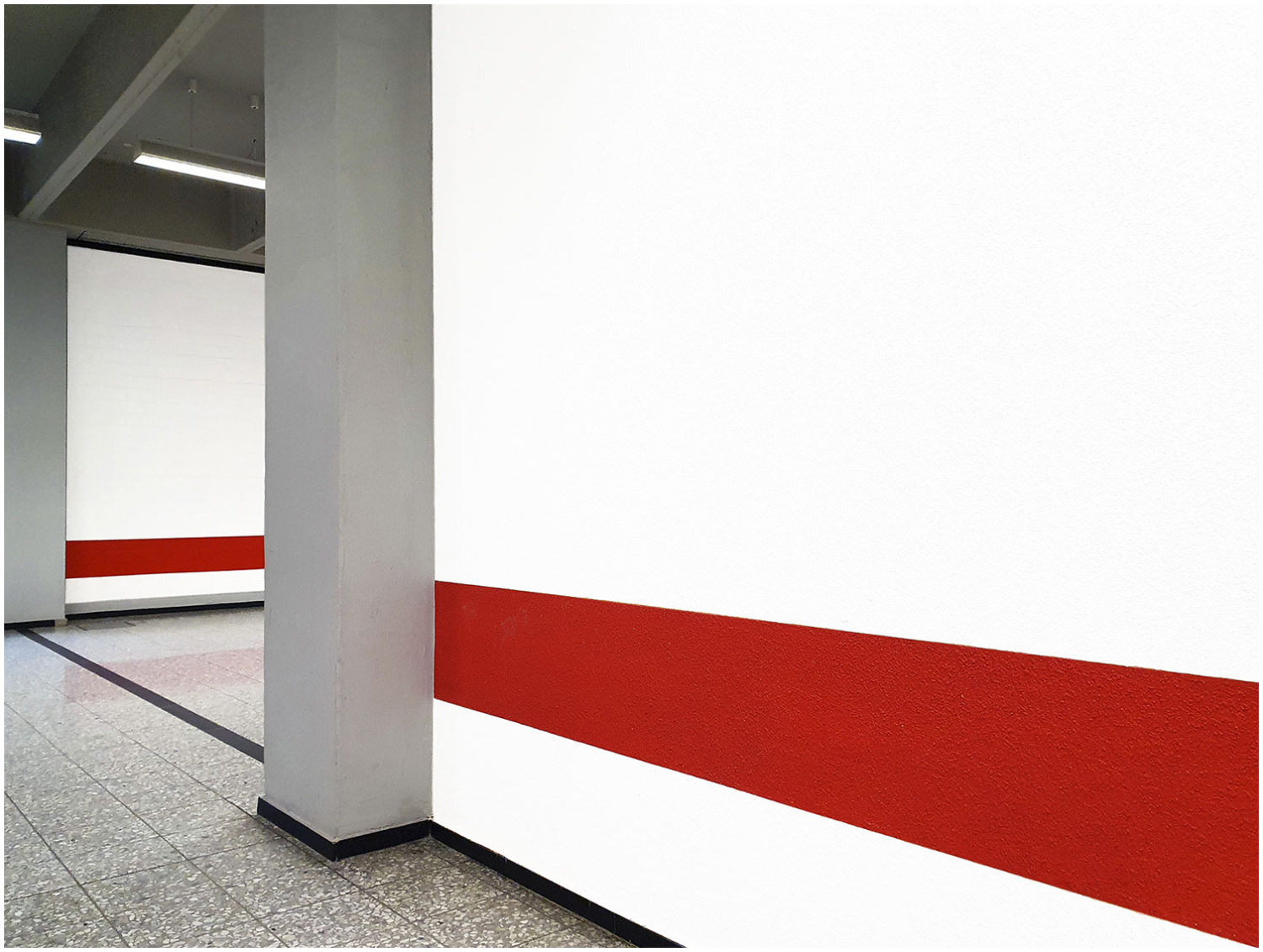 Flur mit zwei grauen Säulen und weiß und rot gestrichenen Wänden