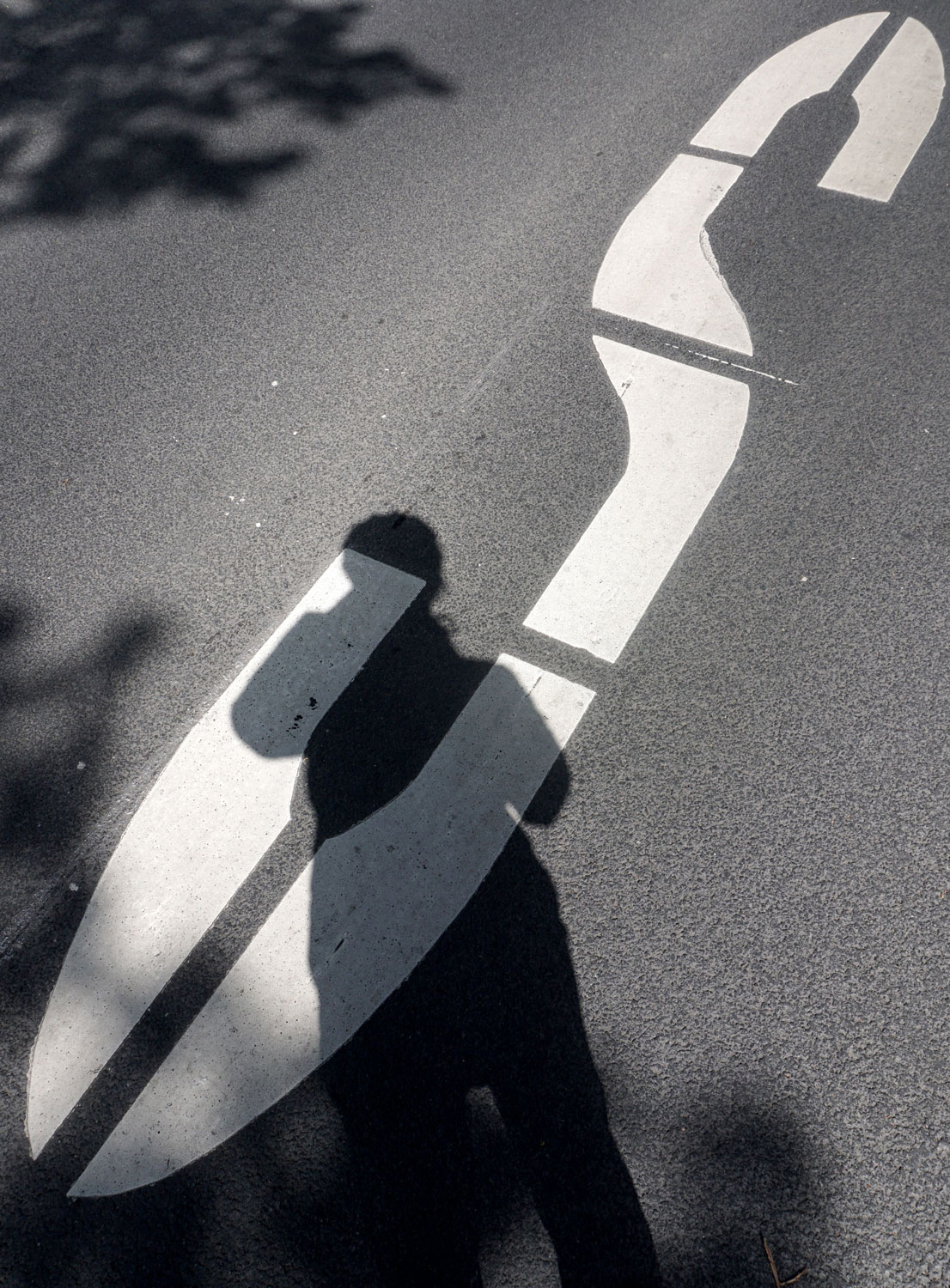 Schattenriss einer Person auf einer Straße mit einem aufgemalten großem S