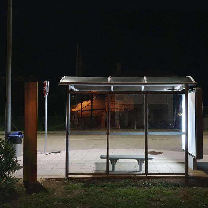 Farbfotografie, die eine Bushaltestelle im Abendlicht zeigt.